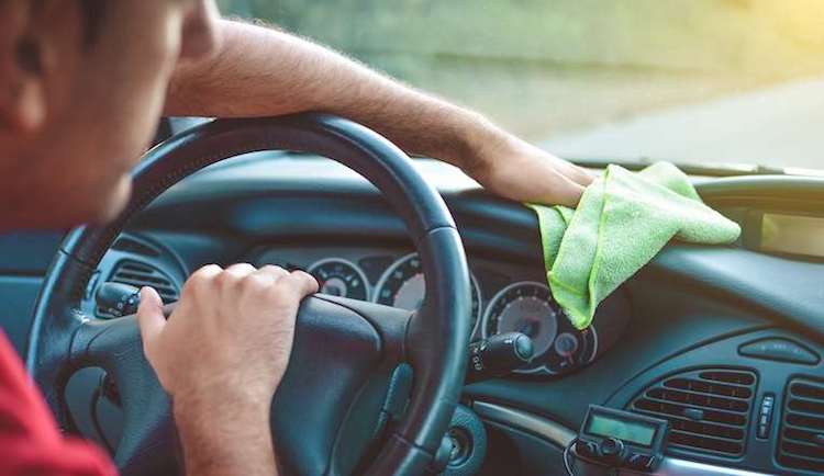 man wiping down car dashboard