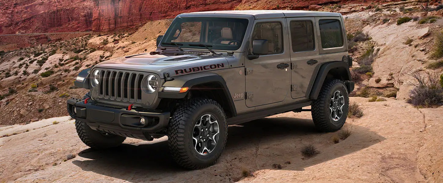 Greyish Brown 2023 Jeep Wrangler parked on a slab in the desert area