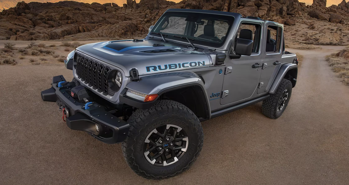 Front angled view of a 2024 Jeep Wrangler 4xe driving on a dirt path