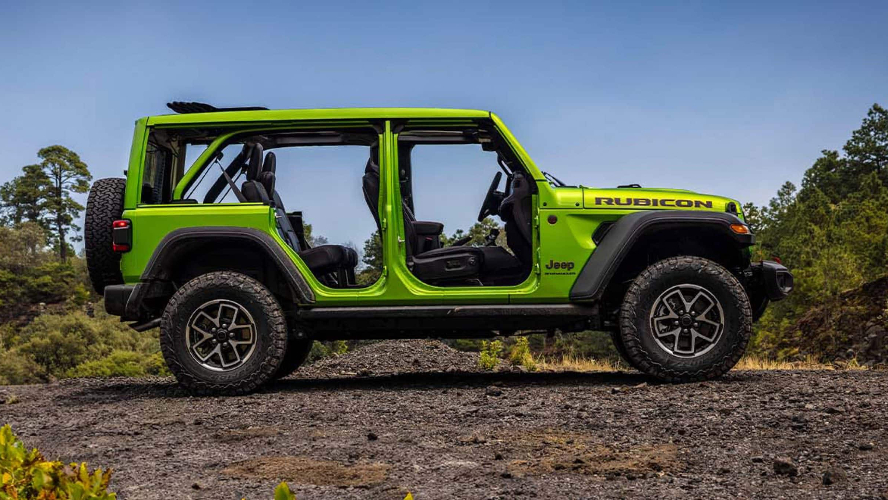 A lime green Jeep Wrangler in profile with its doors off, parked off-road in a clearing.