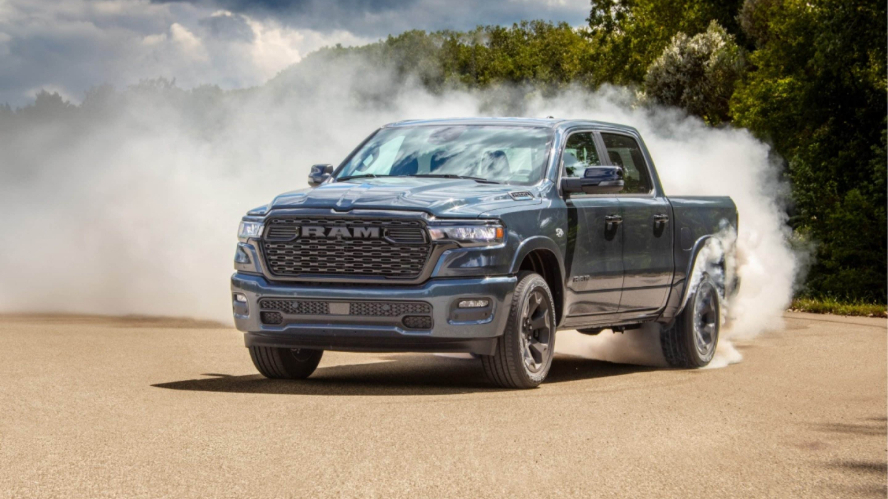 A light blue RAM 1500 kicking up dust or smoke in a drive test area.