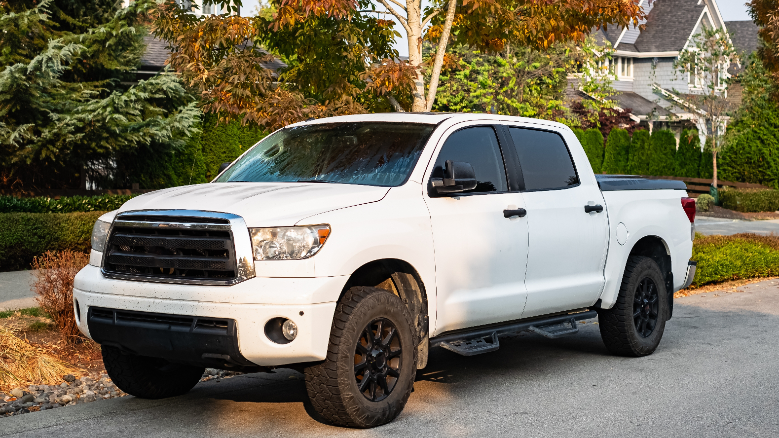 A white pickup truck parked by the curb in a suburban neighborhood.